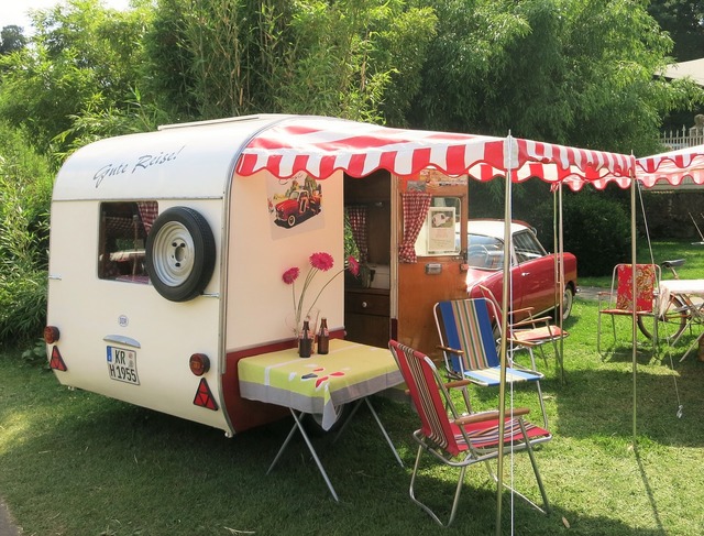 A vintage trailer with a red and white striped canopy