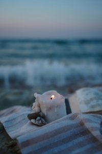Candle on Blanket on the sand next to water