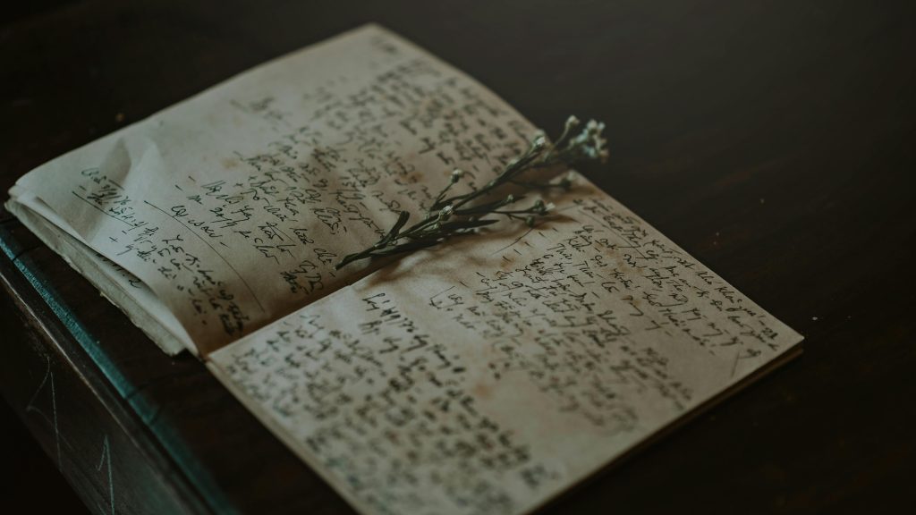 Worn, handwritten journal with dried flowers as a bookmark
