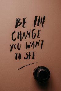 The words be the change you want to see in black on a brown background